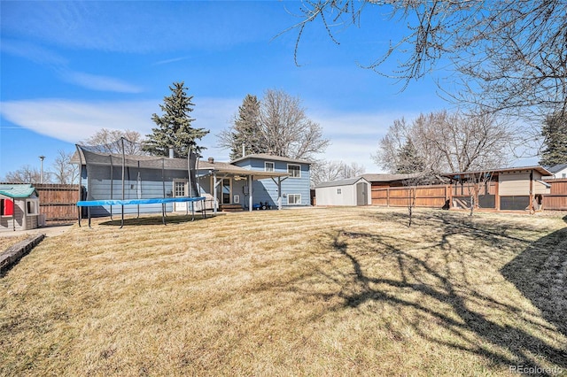 view of yard featuring a storage unit, a fenced backyard, a trampoline, and an outdoor structure