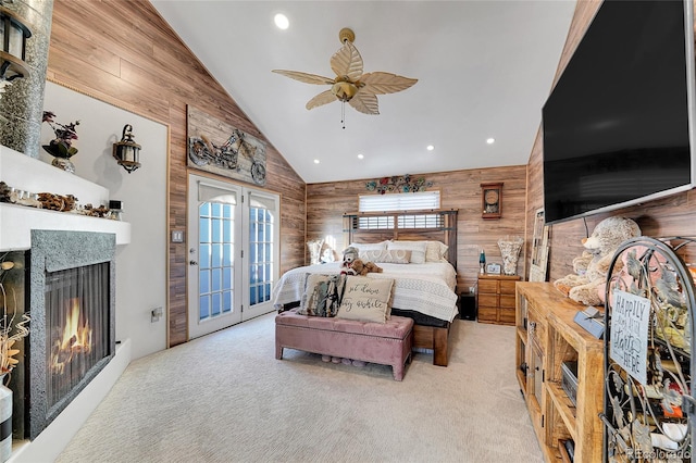 bedroom with ceiling fan, wood walls, light carpet, and access to outside