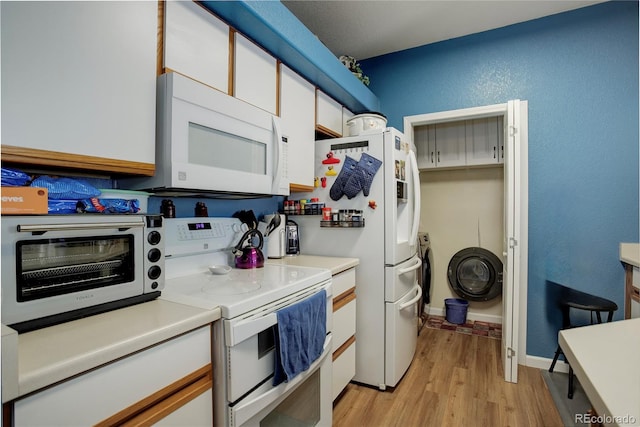 kitchen with a toaster, light wood finished floors, light countertops, white cabinetry, and white appliances