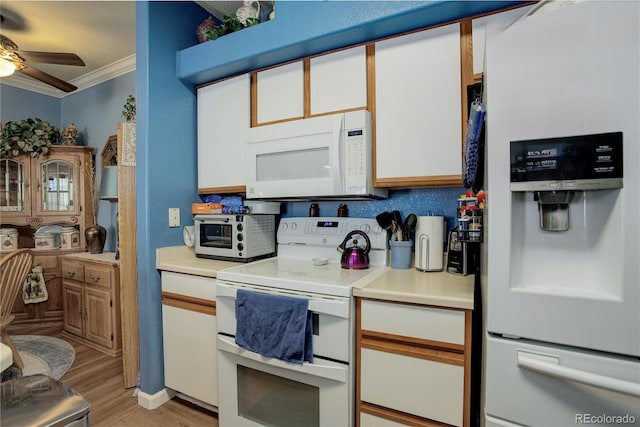 kitchen with ornamental molding, light countertops, white appliances, and white cabinetry