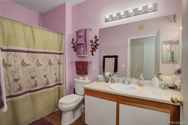 bathroom with toilet, visible vents, wood finished floors, and vanity