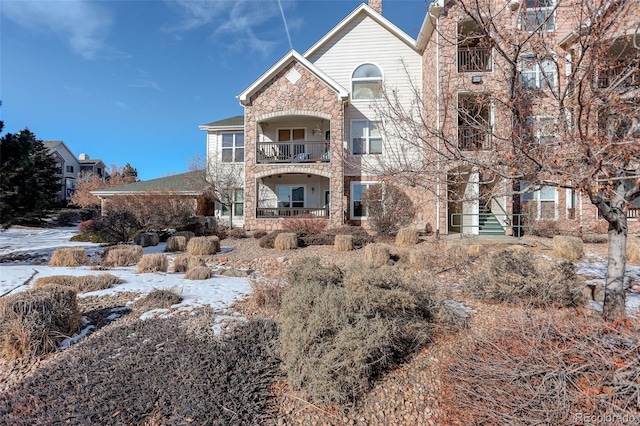 view of front of property with stone siding and a balcony