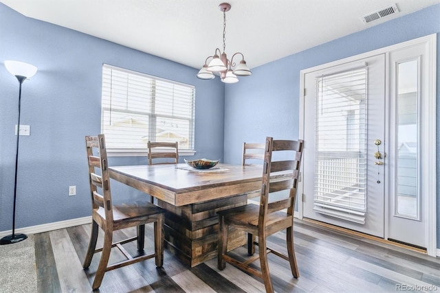 dining space with a chandelier, baseboards, and wood finished floors
