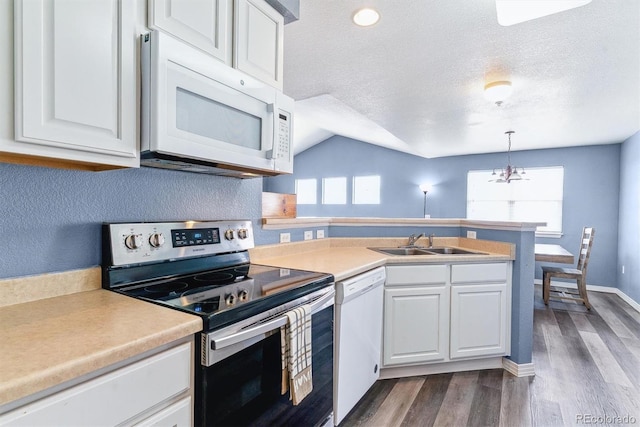kitchen with white appliances, a sink, a peninsula, white cabinets, and dark wood finished floors