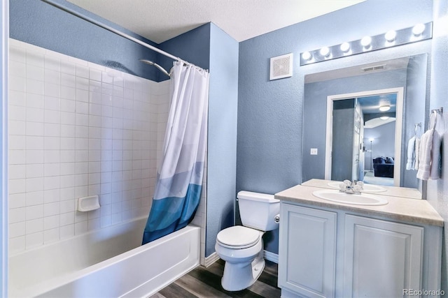 bathroom featuring a textured wall, wood finished floors, toilet, shower / bath combo, and vanity