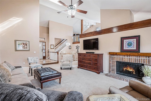 carpeted living area featuring a ceiling fan, stairway, a brick fireplace, high vaulted ceiling, and beam ceiling