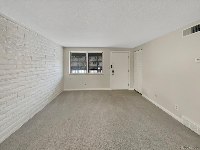 carpeted empty room with a textured ceiling