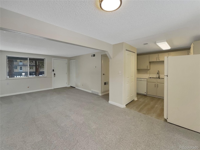 unfurnished living room with light carpet, a textured ceiling, and sink