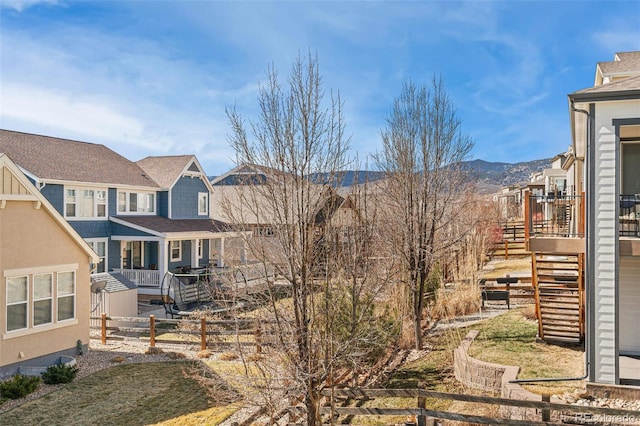 view of side of home with a residential view, stairs, fence, a mountain view, and stucco siding