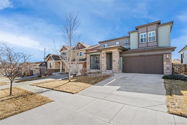 view of front of home with driveway, stone siding, a residential view, an attached garage, and fence