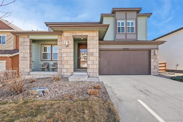 view of front of home with an attached garage, stone siding, a porch, and concrete driveway