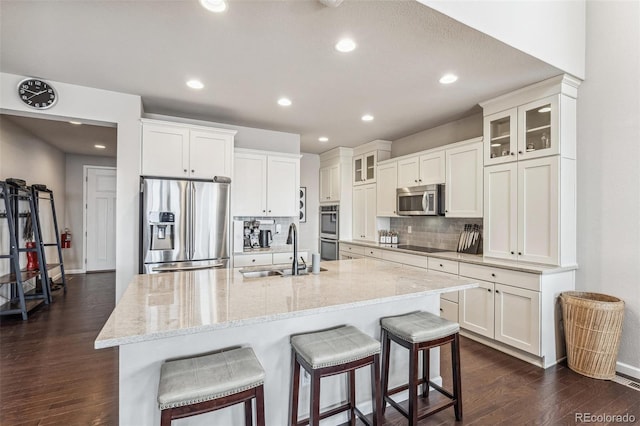 kitchen featuring dark wood-style floors, tasteful backsplash, appliances with stainless steel finishes, white cabinetry, and a sink