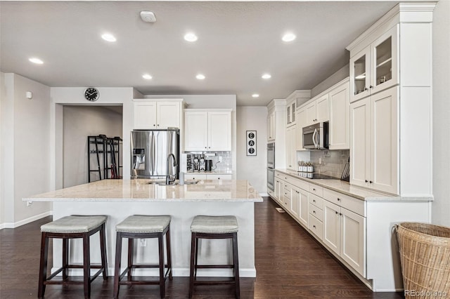 kitchen with appliances with stainless steel finishes, white cabinetry, a sink, and a kitchen bar