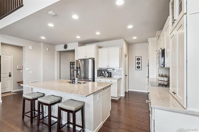 kitchen featuring appliances with stainless steel finishes, white cabinets, dark wood finished floors, and backsplash