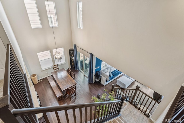 interior space featuring baseboards, stairway, wood finished floors, a high ceiling, and a chandelier