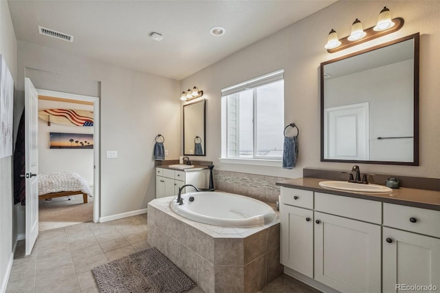 ensuite bathroom featuring a garden tub, two vanities, a sink, visible vents, and tile patterned floors