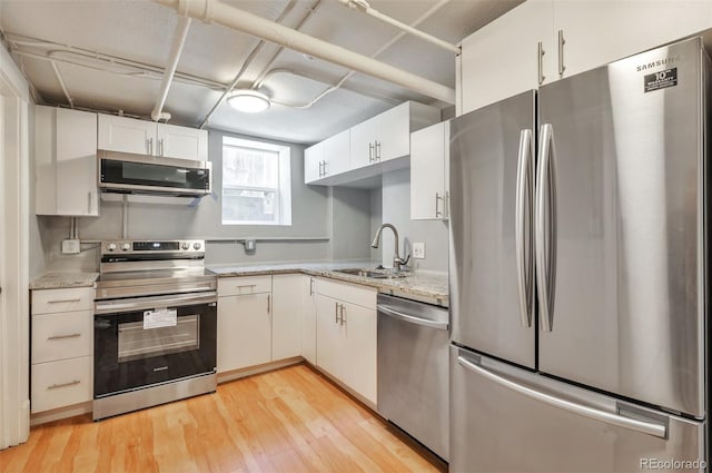 kitchen featuring white cabinetry, light wood-style floors, appliances with stainless steel finishes, and a sink