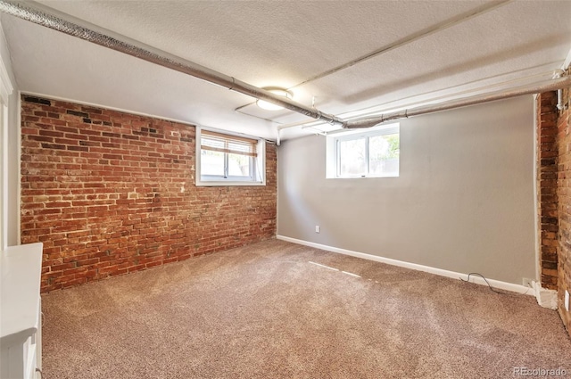 basement featuring carpet flooring, brick wall, and a textured ceiling