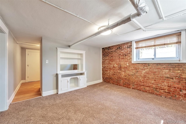 unfurnished living room with carpet, a textured ceiling, baseboards, and brick wall