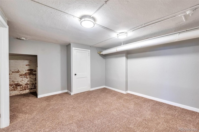 finished below grade area featuring a textured ceiling, carpet floors, and baseboards