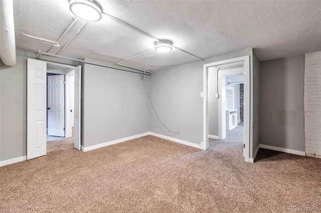 basement featuring baseboards, carpet flooring, and a textured ceiling