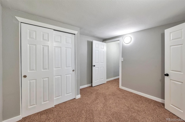 unfurnished bedroom with carpet, a textured ceiling, a closet, and baseboards