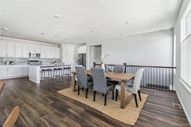 dining space featuring a wealth of natural light, visible vents, dark wood-style flooring, and a textured ceiling