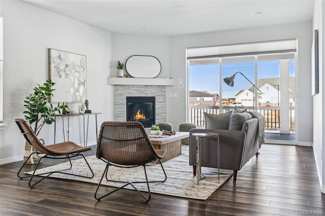 living area with a glass covered fireplace, wood finished floors, and baseboards