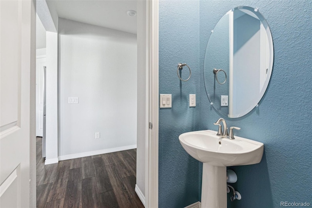 bathroom with baseboards, wood finished floors, and a textured wall