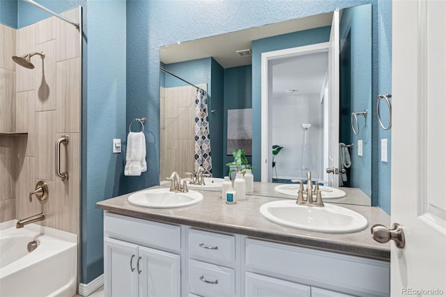 bathroom with double vanity, shower / bathtub combination with curtain, a textured wall, and a sink