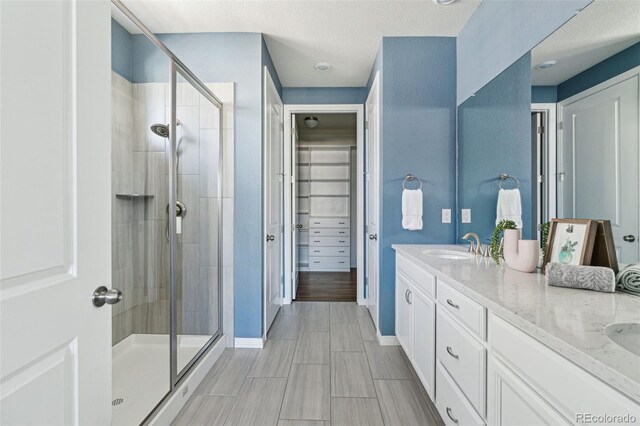 bathroom featuring double vanity, baseboards, a stall shower, and a sink