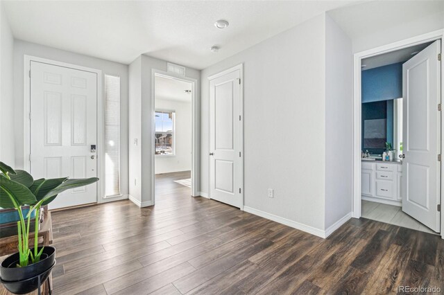 foyer entrance with baseboards and dark wood-style flooring