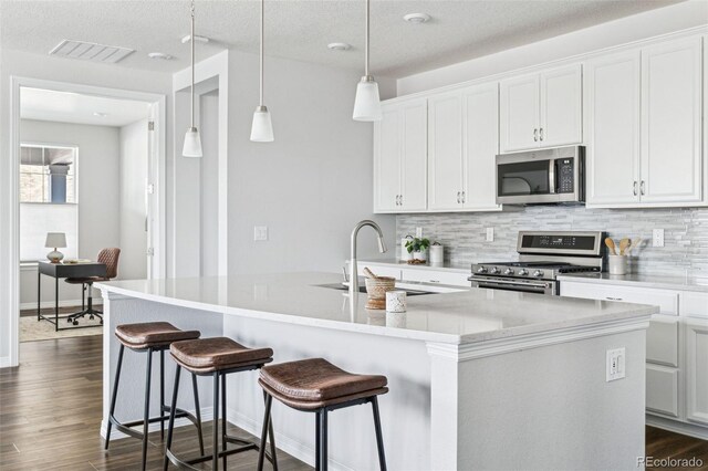 kitchen featuring decorative backsplash, dark wood-type flooring, appliances with stainless steel finishes, and a sink