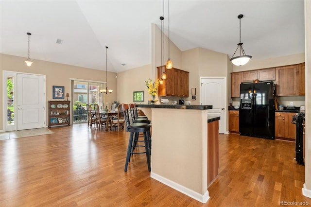 8595 Gold Peak Dr Unit A, Highlands Ranch, CO 80130 - kitchen with black fridge, dark countertops, brown cabinets, high vaulted ceiling, and a peninsula