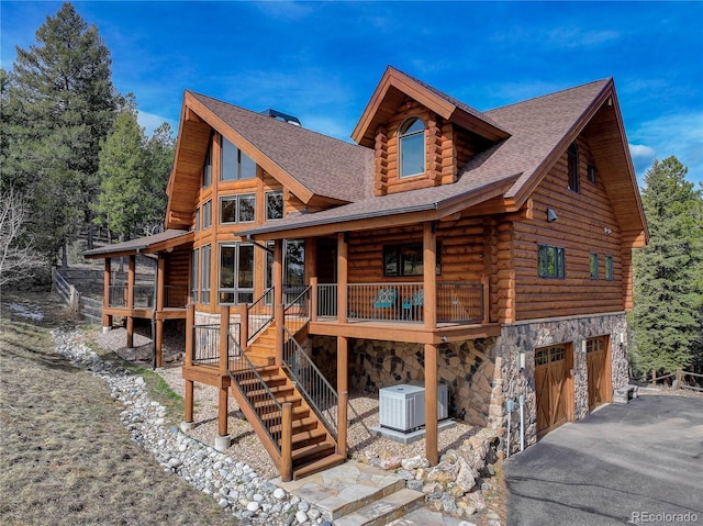 14753 Kit Carson Peak Trl, Pine, CO 80470 - rear view of house with log exterior, central air condition unit, stone siding, a garage, and roof with shingles