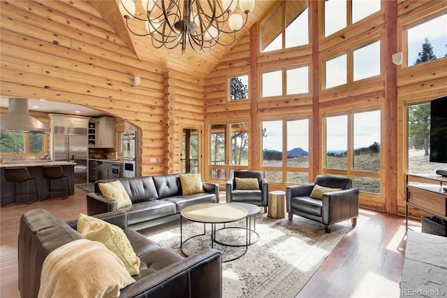 14753 Kit Carson Peak Trl, Pine, CO 80470 - living room with high vaulted ceiling, arched walkways, plenty of natural light, a chandelier, and rustic walls