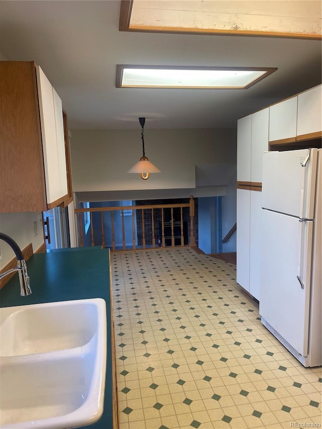 kitchen featuring hanging light fixtures, sink, white cabinets, and white refrigerator