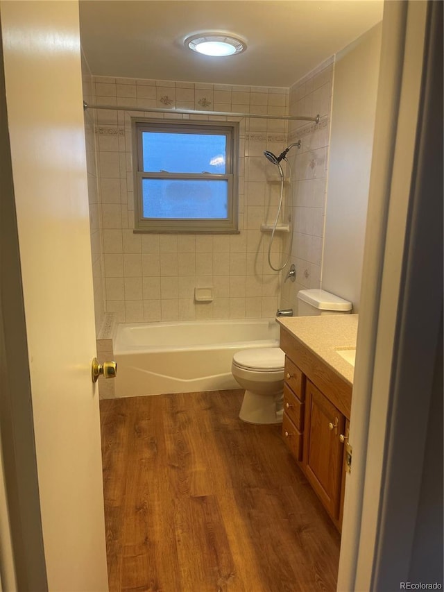 full bathroom featuring vanity, wood-type flooring, tiled shower / bath, and toilet