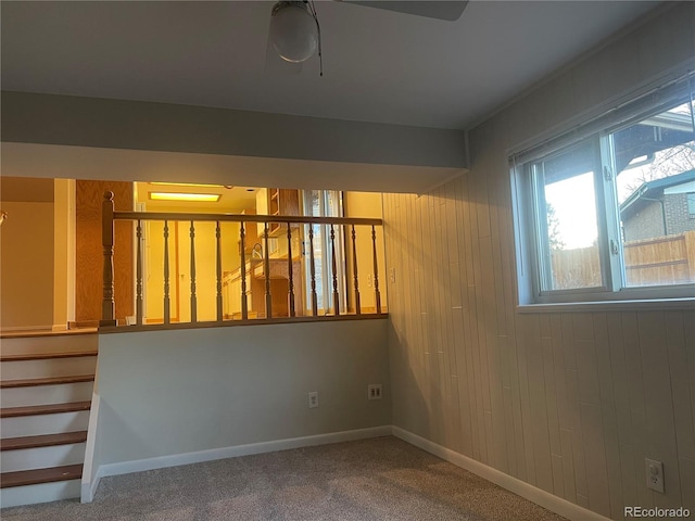 carpeted empty room featuring wooden walls