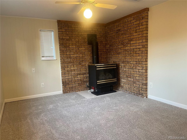 unfurnished living room featuring ceiling fan, carpet floors, and a wood stove