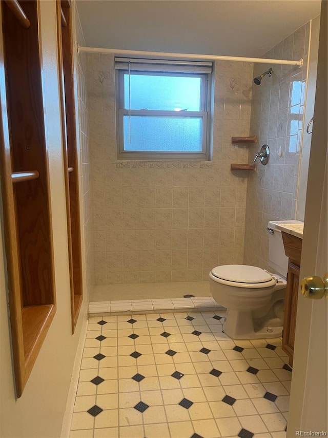 bathroom with vanity, toilet, and a tile shower