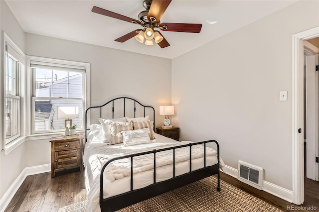 bedroom with ceiling fan, visible vents, baseboards, and wood finished floors