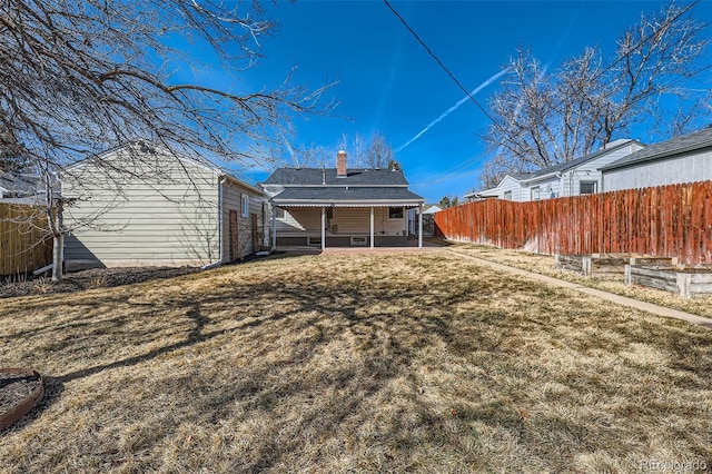 back of property featuring a patio, a yard, fence, and a chimney