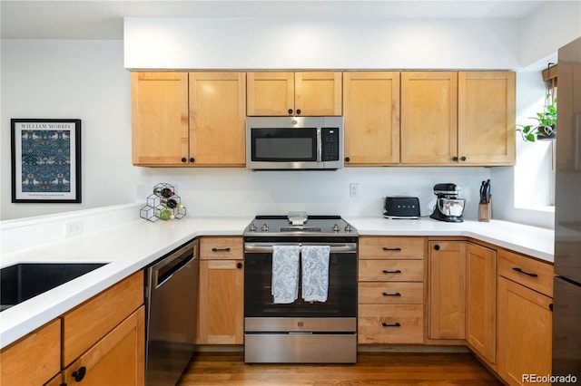 kitchen with stainless steel appliances, hardwood / wood-style floors, and light brown cabinets