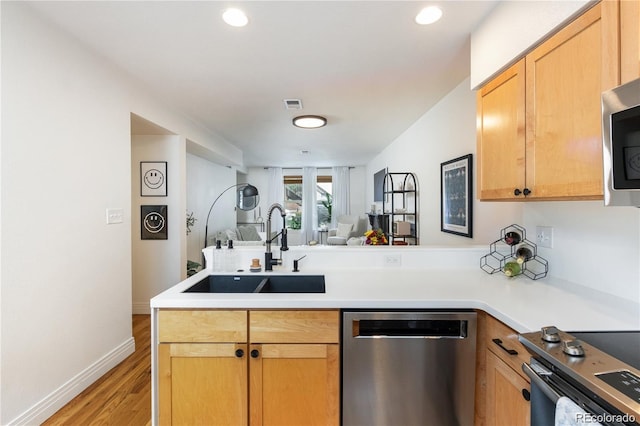 kitchen featuring sink, kitchen peninsula, stainless steel appliances, light brown cabinets, and light hardwood / wood-style flooring