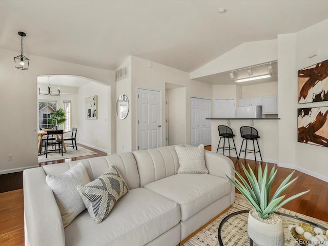 12335 E 2nd Dr, Aurora, CO 80011 - living area featuring wood finished floors, a chandelier, arched walkways, baseboards, and lofted ceiling