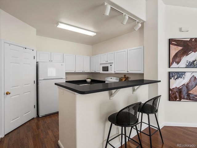 12335 E 2nd Dr, Aurora, CO 80011 - kitchen featuring white appliances, dark countertops, a kitchen bar, and rail lighting