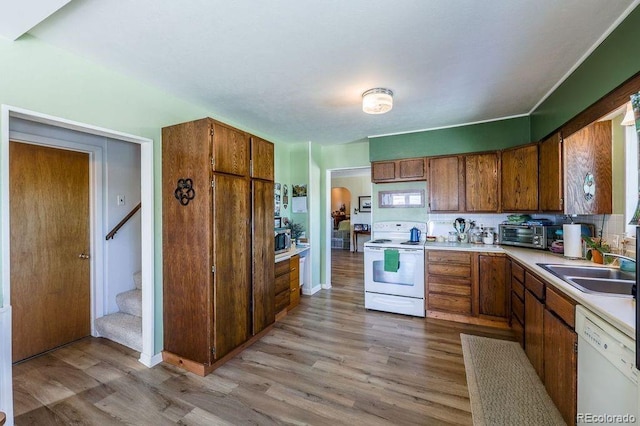 kitchen with decorative backsplash, white appliances, light hardwood / wood-style floors, and sink