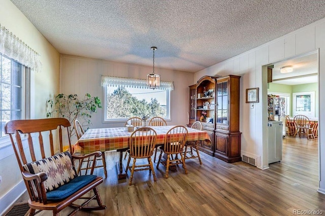 dining room featuring a textured ceiling and dark hardwood / wood-style flooring