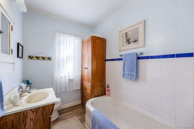 bathroom featuring a bathing tub, crown molding, toilet, vanity, and hardwood / wood-style flooring